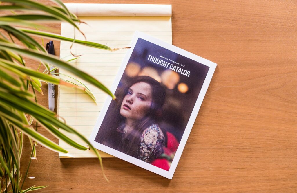 Štampani katalog sa dizajnom korica položen na drvenu podlogu, primer profesionalne izrade kataloga.