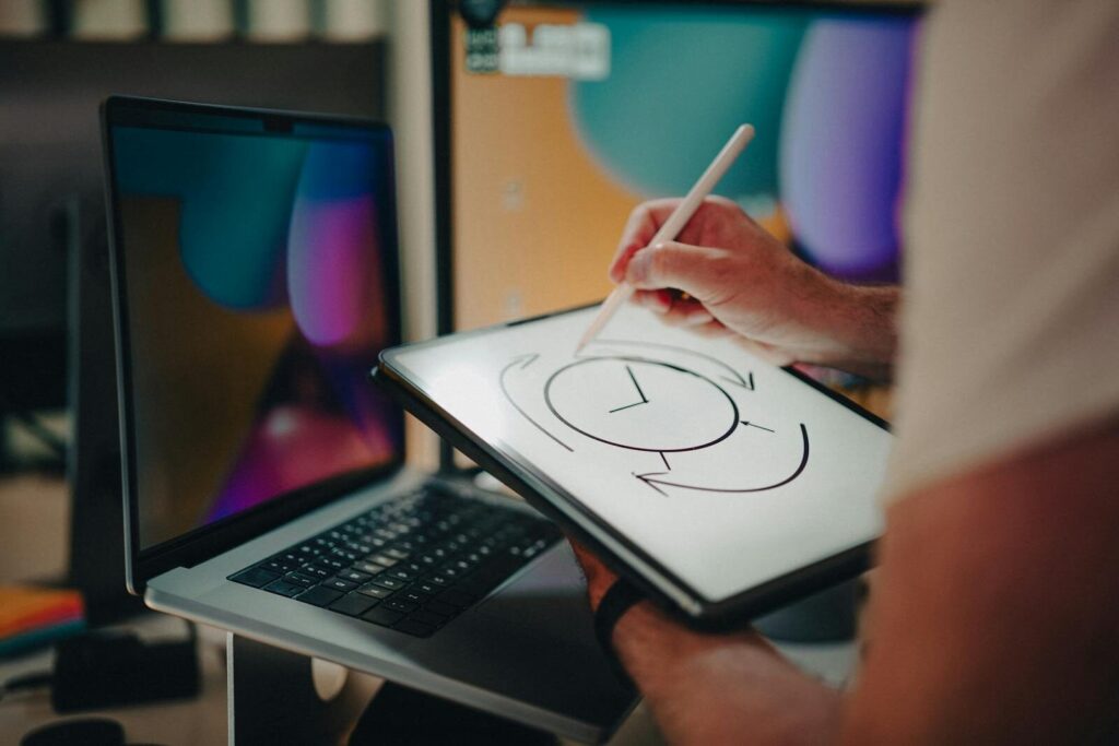 Person using a stylus on a graphic tablet for design in a modern office setting.