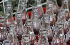 A detailed view of empty glass soda bottles arranged in a red crate, showcasing a repetitive pattern and reflections.