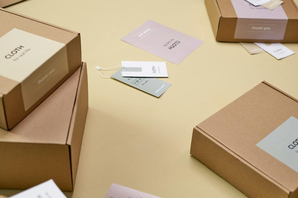 Kako odabrati nalepnice za staklo, plastiku, karton i metalnu ambalažu 3 Simple and minimalist cardboard packaging boxes with labels on a yellow surface.