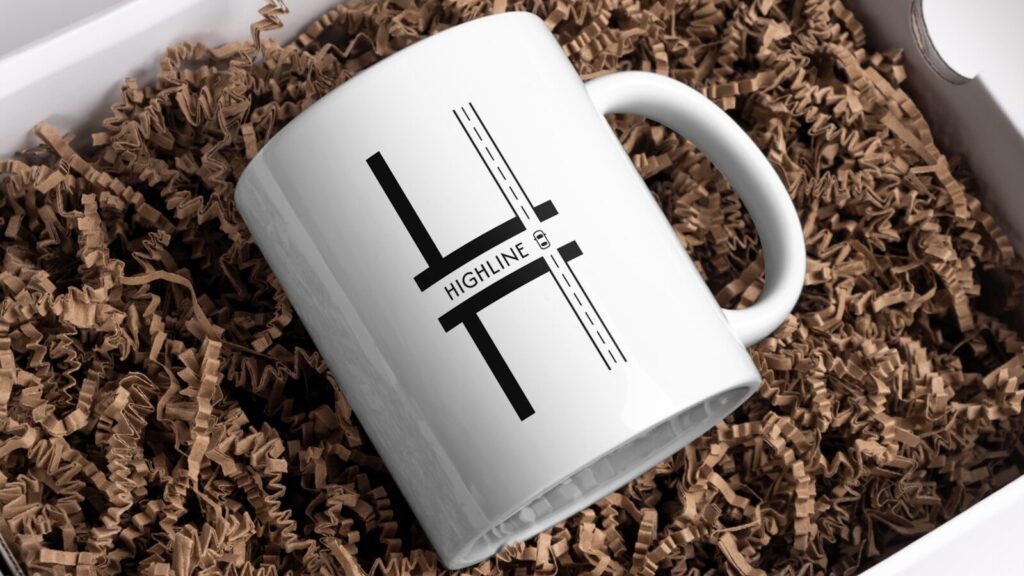 A white mug with a design is in a box.