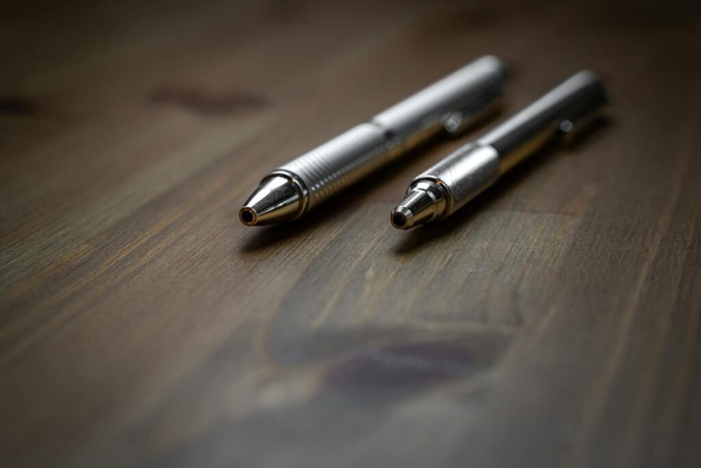 Kako pripremiti materijal za sajam: od flajera do promo proizvoda 3 Close-up view of two silver ballpoint pens placed on a wooden surface, ideal for business themes.