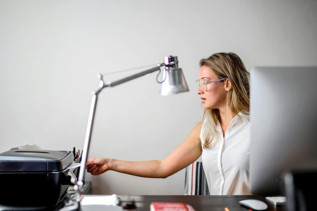 Zašto su probni otisak i kontrola kvaliteta važni kod B2B štampe 4 Woman in modern office setting using printer, blending technology with contemporary style.